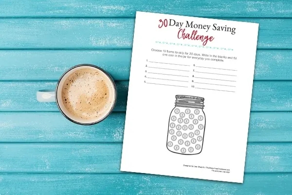 30 day money saving challenge printable on a blue table with a coffee mug.