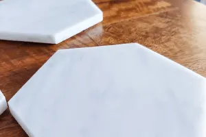 Two white marble coasters on a table. 