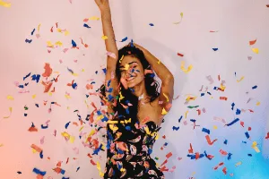 Woman smiling with colorful confetti falling around them.