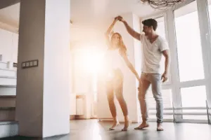 couple dancing at home with the sun shining in the window. 