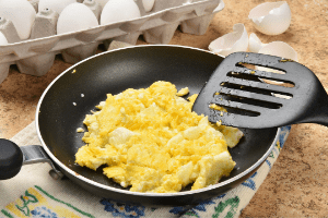 Scrambled eggs cooked in a frying pan.