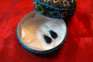 Black earrings inside a jeweled box.