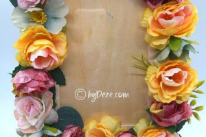 Photo frame covered in yellow and pink flowers. 