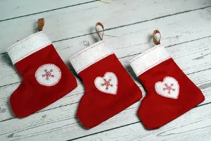 Three red stocking holders with a white heart on each stocking. 