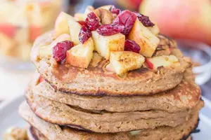 Stack of apple oatmeal pancakes with cut up apples on top.