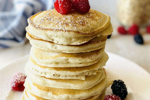 Pile of oat pancakes on a plate with berries. 
