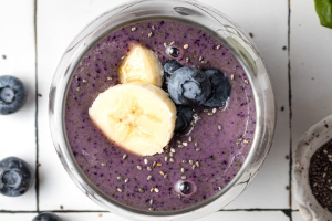 Breakfast smoothie blueberry with cut up banana's on top in a glass jar.