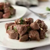 small steak bites piled on a white plate.