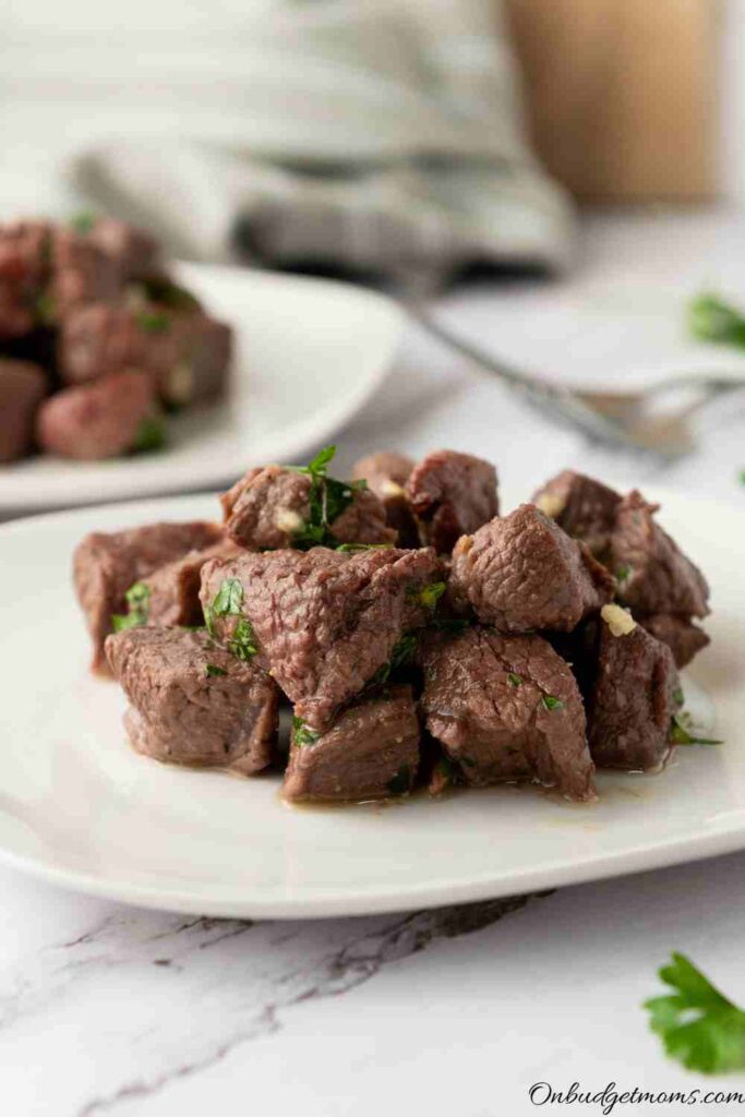 small steak bites piled on a white plate.